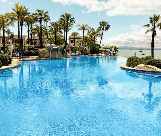 Stor pool med palmer och utsikt över havet. (AI-genererad text)