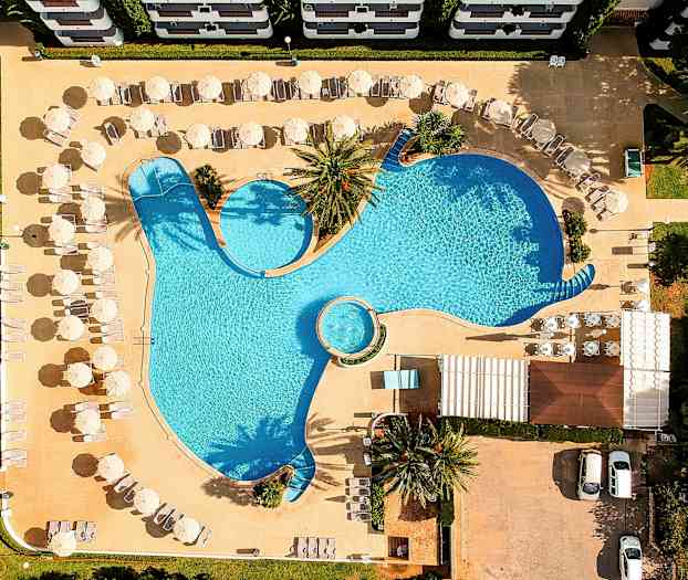 Flygfoto av en pool med solstolar och parasoller runtom. (AI-genererad text)