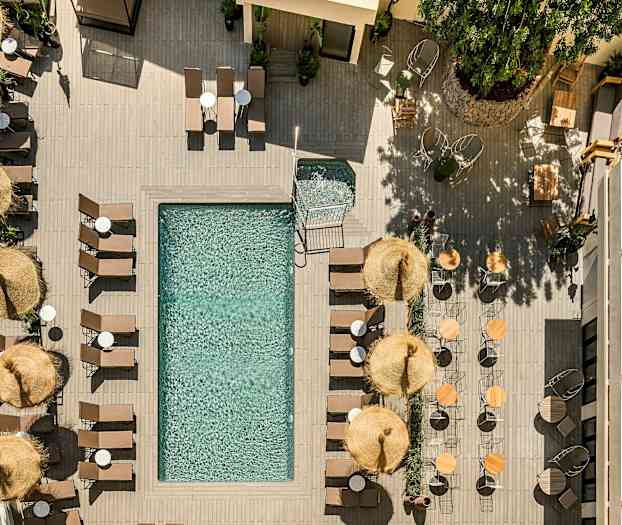 Fågelperspektiv av en pool omgiven av solstolar, parasoller och bord. (AI-genererad text)