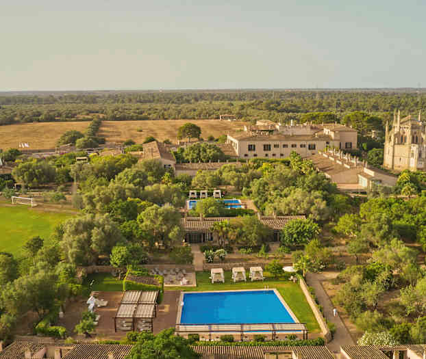 Flygbild av lantlig semesteranläggning med pool och trädgårdar. (AI-genererad text)