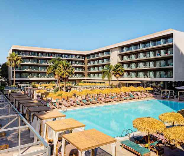 Ett modernt hotell med en stor pool, solstolar och parasoller, omgett av balkonger. (AI-genererad text)