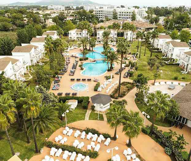 Ett semesterhotell med poolområde, grönområden och byggnader i bakgrunden. (AI-genererad text)