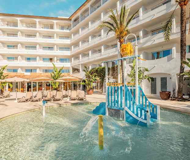 Utomhuspoolområde med barnlekplats och solstolar framför hotellbyggnad. (AI-genererad text)