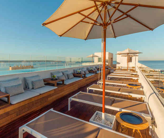 Vy över en modern takterrass med solsängar och parasoller mot havet. (AI-genererad text)