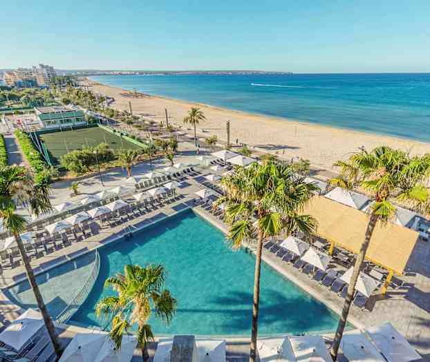 Utsikt över en pool med solstolar och parasoll vid en strand i en stadsmiljö. (AI-genererad text)