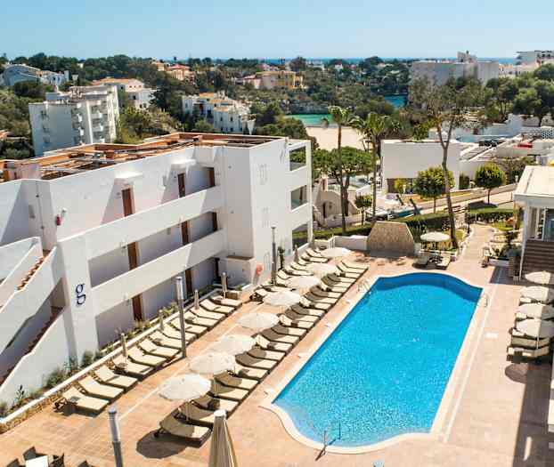 Bild av ett hotellområde med en pool och solstolar. I bakgrunden syns grönområden och byggnader. (AI-genererad text)