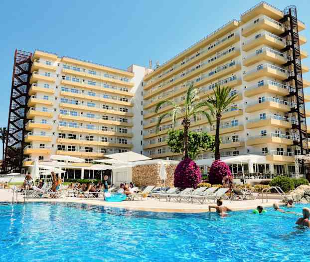 Bild av ett hotell med flera våningar, inklusive en utomhuspool där människor simmar och relaxar. Det finns palmer och blommor runt poolområdet. (AI-genererad text)