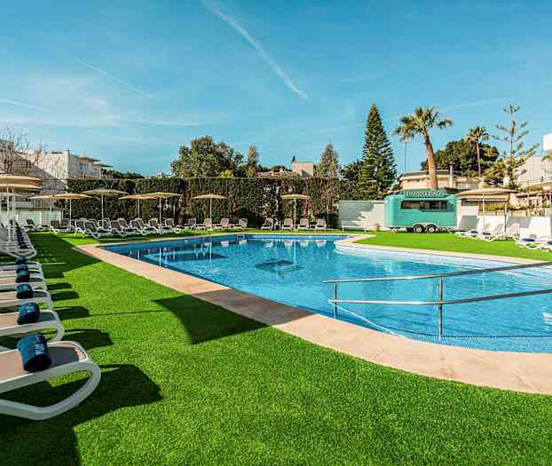 Utomhuspool med solstolar och gröna omgivningar. (AI-genererad text)