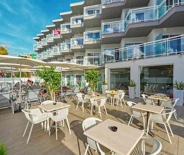 Utomhusområde med bord och stolar samt solstolar vid ett hotell med balkonger. (AI-genererad text)