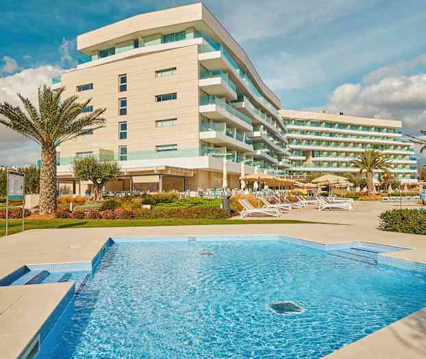 Bild av ett hotell med moderna byggnader, en swimmingpool och exteriör loungeområden. (AI-genererad text)