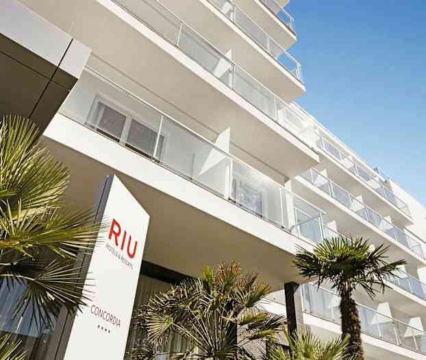 En modern hotellbyggnad med balkonger och palmer i förgrunden. (AI-genererad text)