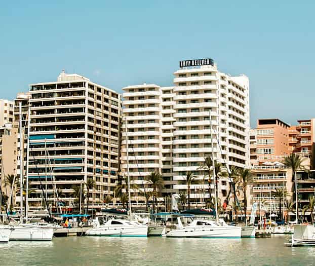 En bild av en hamn med segelbåtar och höga byggnader i bakgrunden. (AI-genererad text)