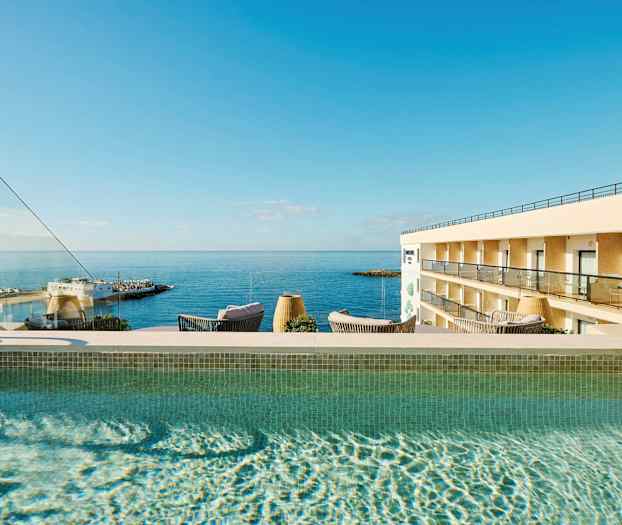 Utomhuspool med utsikt över havet och en hotellbyggnad. (AI-genererad text)