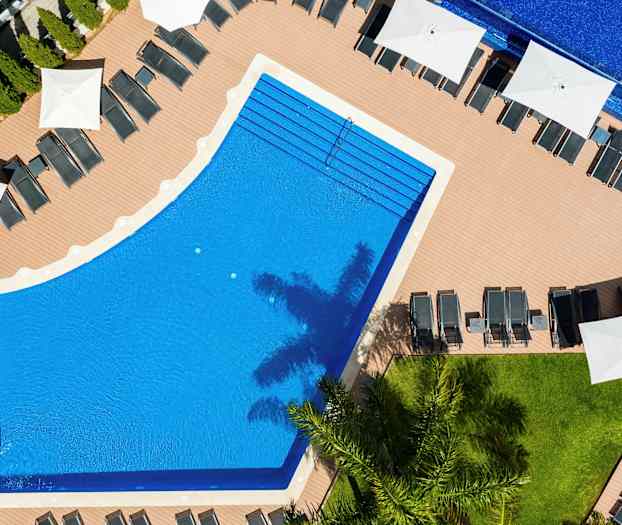 Flygfoto av en pool omringad av solstolar och parasoller. (AI-genererad text)
