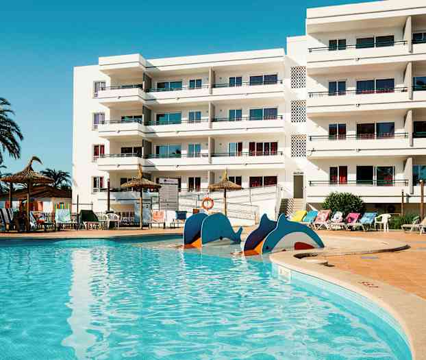 En swimmingpool framför en vit byggnad med balkonger. (AI-genererad text)