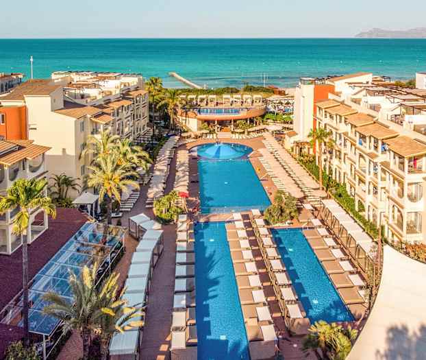 Utsikt över en resort med pooler och havet i bakgrunden. (AI-genererad text)