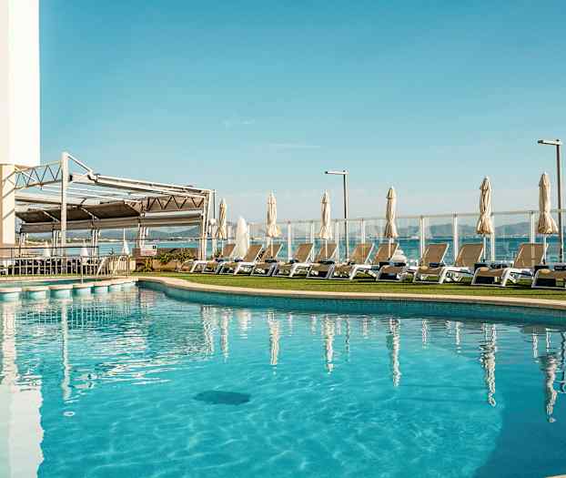 Utomhuspool med solsängar och parasoller vid sidan. (AI-genererad text)