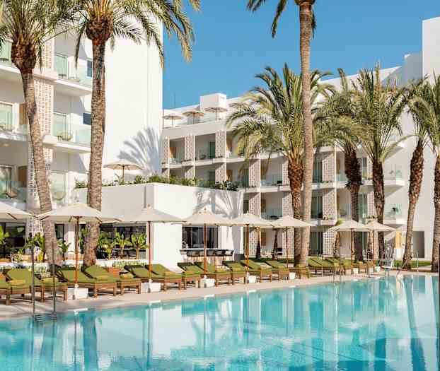 Poolområde med solstolar, parasoller och en vit byggnad i bakgrunden omgivet av palmträd. (AI-genererad text)