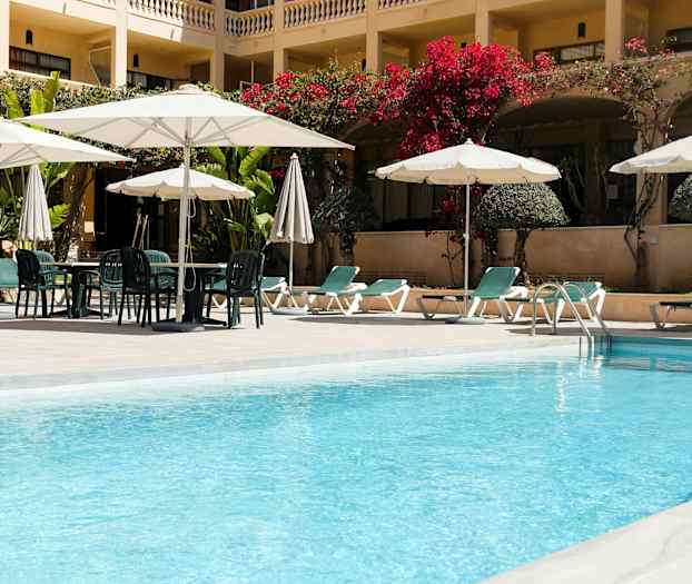 En hotellpool med solstolar och parasoller. (AI-genererad text)