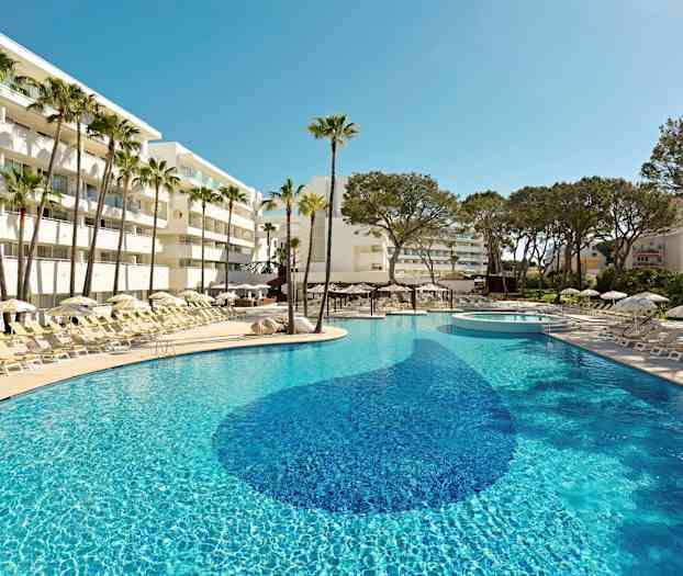 En solig pool omgiven av solsängar, parasoller och palmer vid ett hotell. (AI-genererad text)