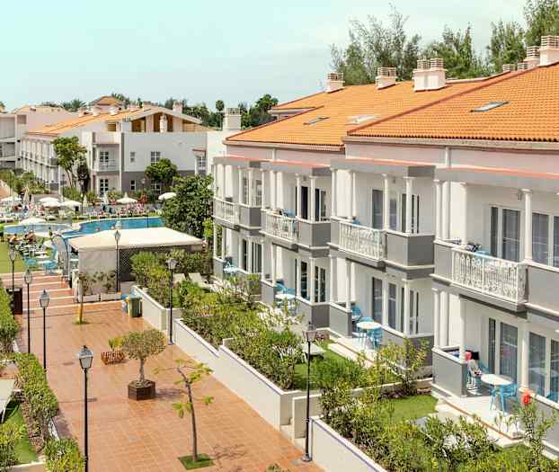 Ett hotellkomplex med flera byggnader, poolområde och trädgård. (AI-genererad text)