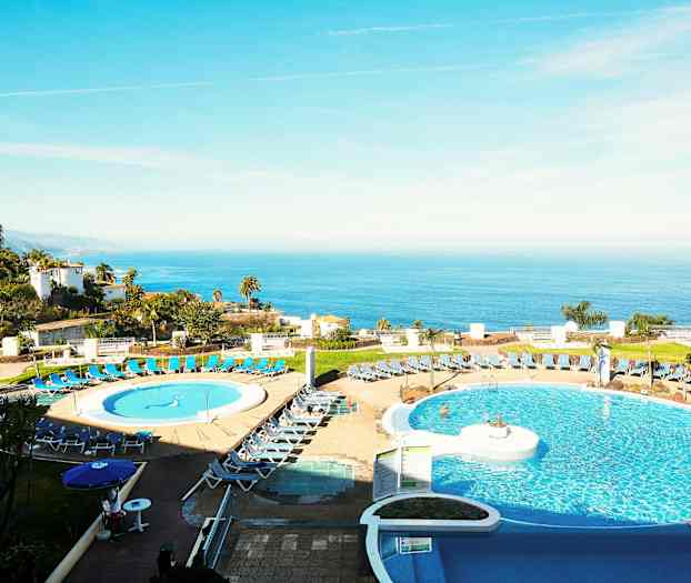 Bild av ett hotell med poolområde i förgrunden och havsutsikt i bakgrunden. (AI-genererad text)