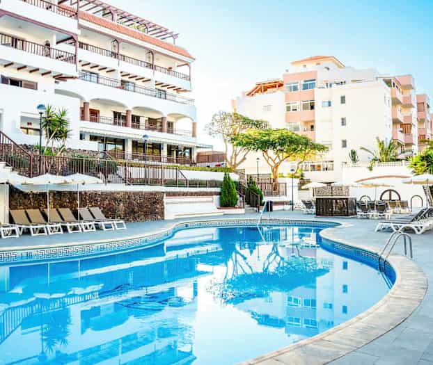 Utomhuspool med solstolar och parasoller vid ett hotell. (AI-genererad text)