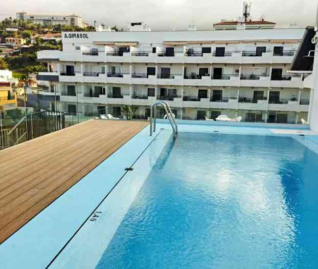 Bild av en swimmingpool med utsikt över ett flerfamiljshus i bakgrunden. (AI-genererad text)