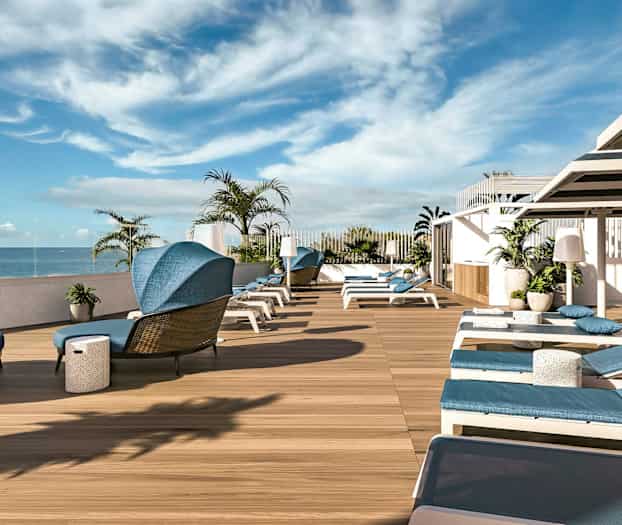 En terrass med solstolar och utsikt över havet. (AI-genererad text)