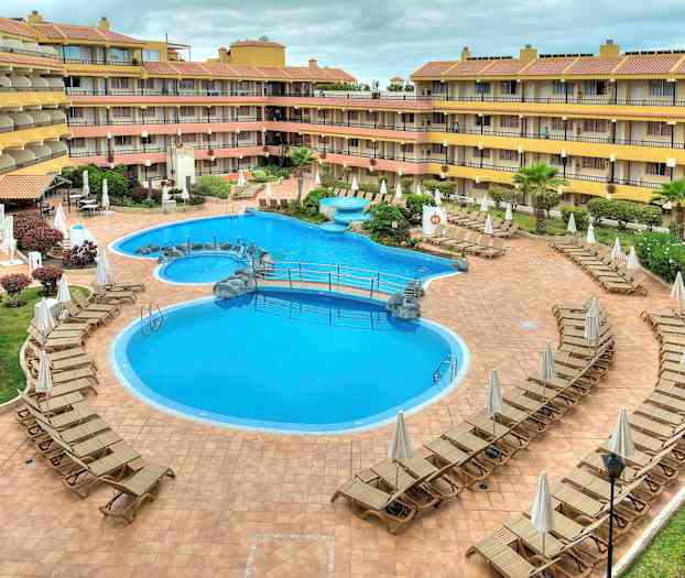 En hotellpool omgiven av solsängar. (AI-genererad text)