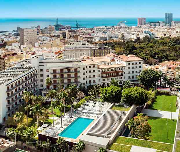 Vy över stadsmiljö med byggnader, grönområden och pool. (AI-genererad text)