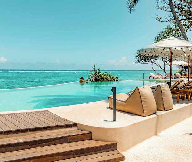 En infinitypool vid havet, omgiven av solstolar och parasoller. (AI-genererad text)