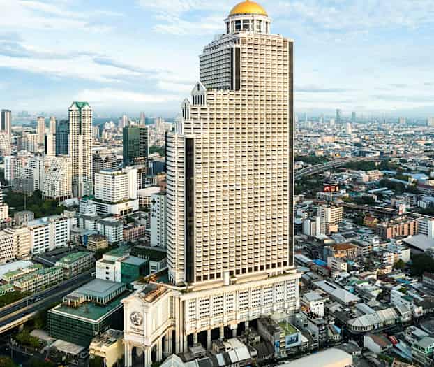 En hög byggnad med kupol på toppen i en stadsbild med andra höga byggnader och infrastruktur. (AI-genererad text)