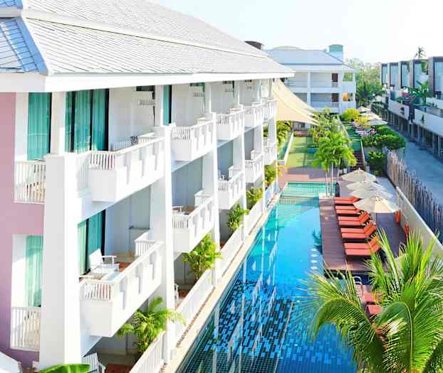 Ett hotell med balkonger och en lång pool bredvid solstolar och parasoller. (AI-genererad text)