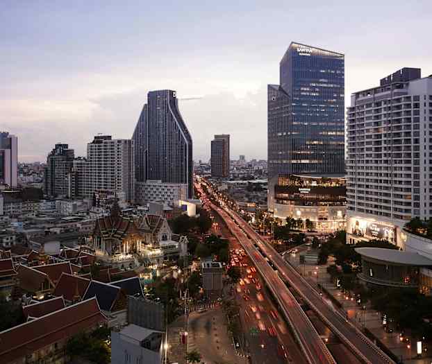 En skyline av en stad med moderna höghus, en livlig väg och traditionella byggnader i förgrunden. (AI-genererad text)