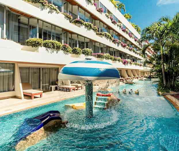 En pool med vattenattraktion vid ett hotell med flera våningar och altaner fyllda med blommor. (AI-genererad text)