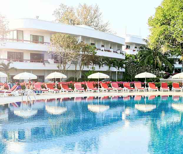 Poolområde med solstolar och parasoller framför ett hotell. (AI-genererad text)