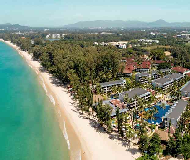 Flygfoto över en semesterort vid en strand med omgivande träd och byggnader. (AI-genererad text)