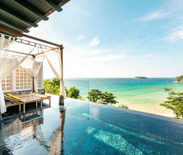 Bilden visar en infinitypool med en solbädd under ett tak med vita tyger, och i bakgrunden syns en sandstrand och havet. (AI-genererad text)