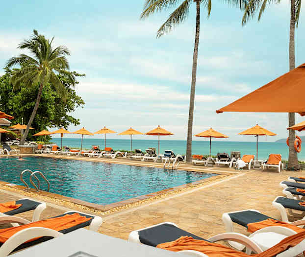 Utomhuspool omgiven av solstolar och parasoller, med utsikt över havet. (AI-genererad text)