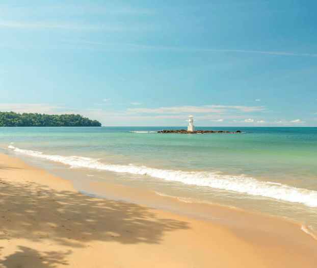 En strand med sand och vågor samt en fyr på en mindre ö. (AI-genererad text)