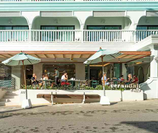 Utomhusbild av ett kafé med parasoller och sittplatser. (AI-genererad text)