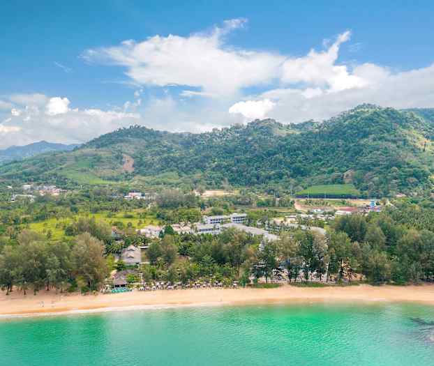 Landskap med en strand, grönskande kullar och byggnader vid vatten. (AI-genererad text)