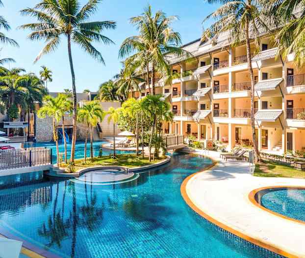 Bild av ett hotellområde med en stor pool omgiven av palmer och byggnader. (AI-genererad text)