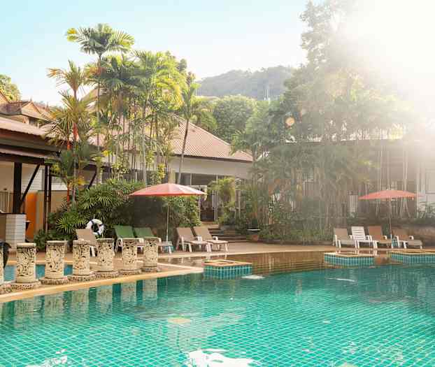 Utomhuspool med solstolar och parasoller, omgiven av grönskande träd. (AI-genererad text)