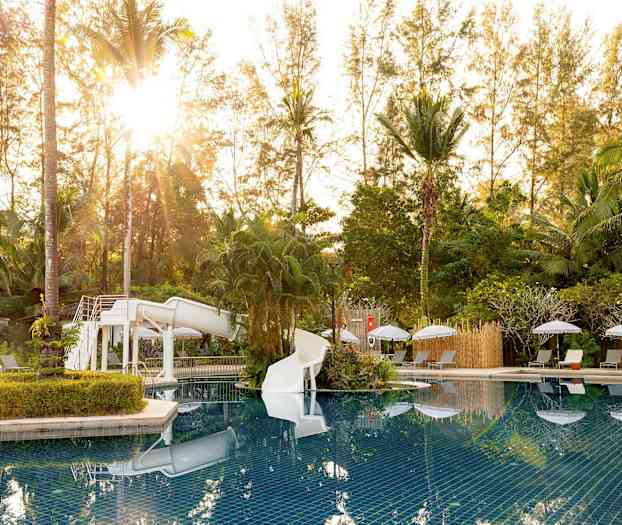 Poolområde med vattenrutschkana, omgiven av solsängar och grönska. (AI-genererad text)