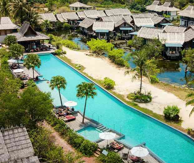 Flera charmiga bungalower vid en pool med solstolar och parasoller, omgivna av grönska. (AI-genererad text)