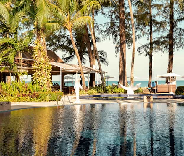 Pool och tropiska träd med utsikt mot havet. (AI-genererad text)