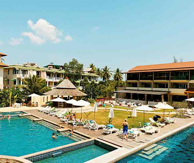 Hotellområde med pool, solstolar och omgivande byggnader. (AI-genererad text)