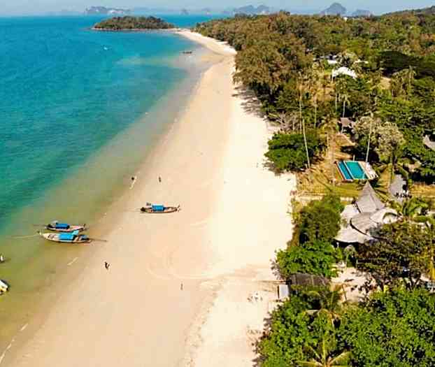 En strand med båtar vid vattnet och gröna träd i närheten. (AI-genererad text)
